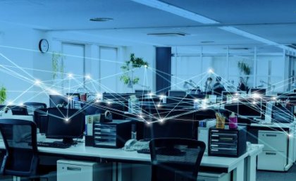 Research has found Australians recognise the benefits of AI in the workplace, but are hesitant. Image: Adobe. An office space with desks, chairs and monitors but no people, and a graphic of connecting lines linking each workstation.